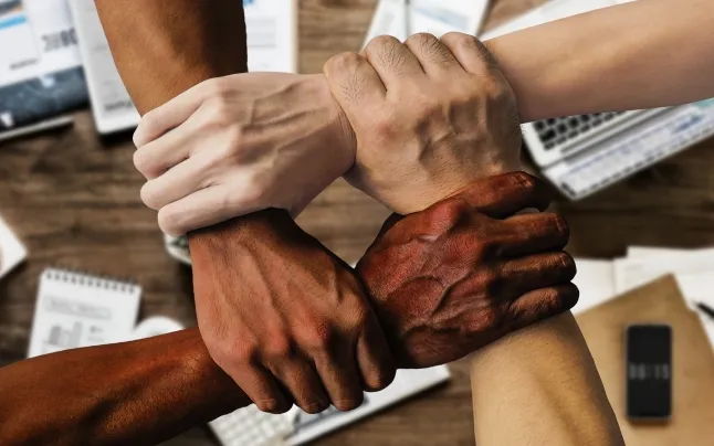 The hands of a team of people clasped.